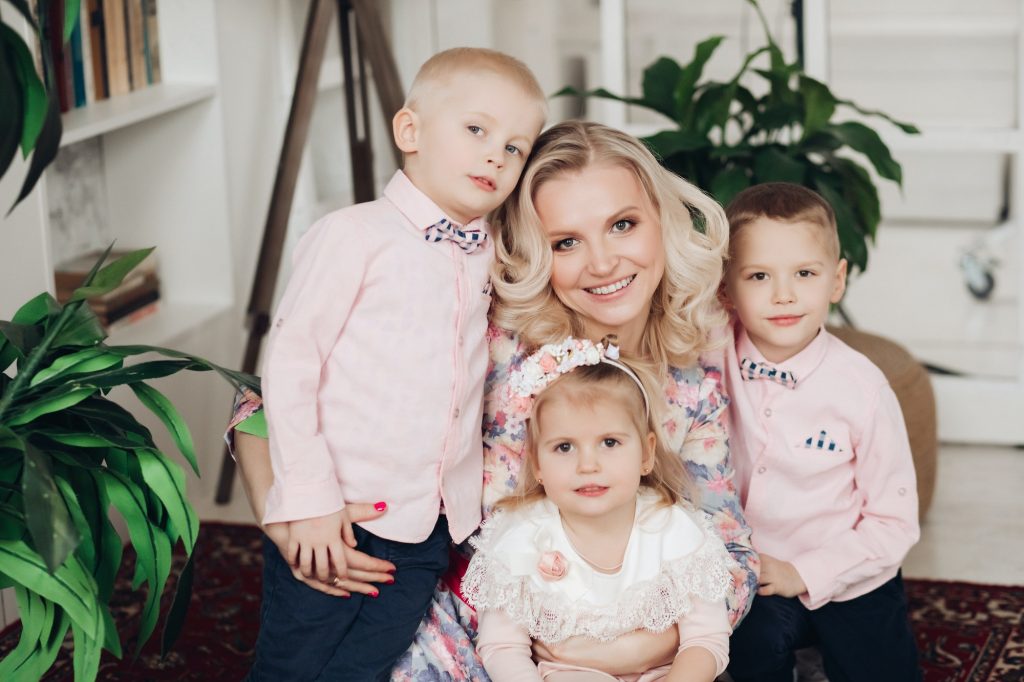 Attractive mother posing with three cute kids at home
